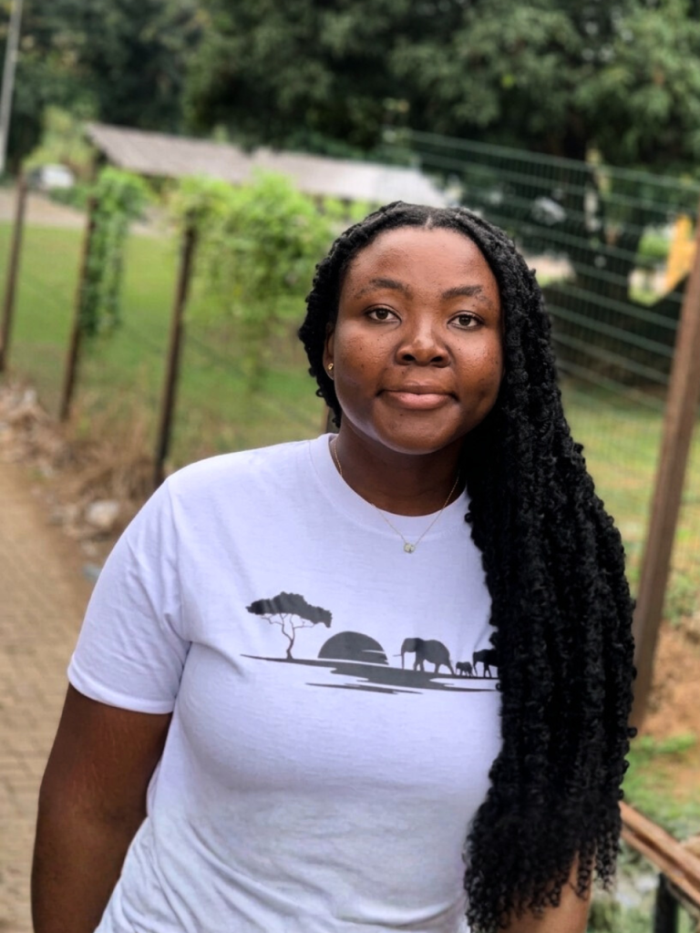 A young black female rocking the white colorway of the Sunset Tee from DripAfrika's collection called The Wild Side